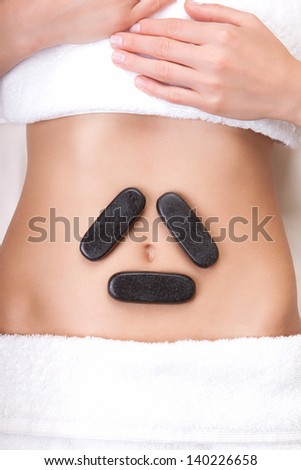 Hot stones on a woman's tummy in a triangle shape around the belly button