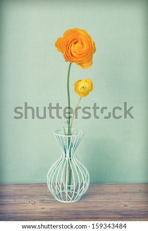 Vintage yellow persian buttercups flowers in a vase on wooden table