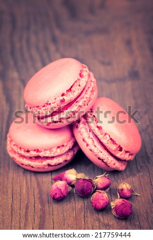 Macaroons with dry roses on retro vintage wooden background