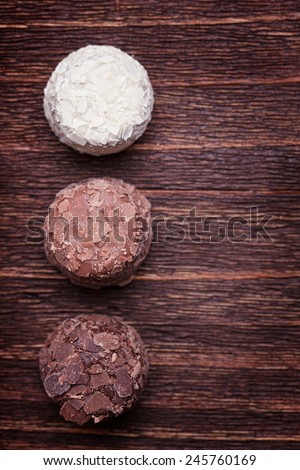 Milk chocolate,white chocolate and dark chocolate truffles on a wooden vintage background