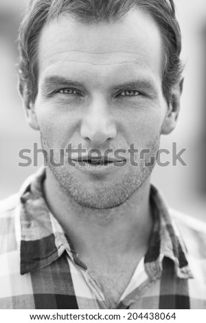 Black and white portrait of man in a checkered shirt. Outdoor shot
