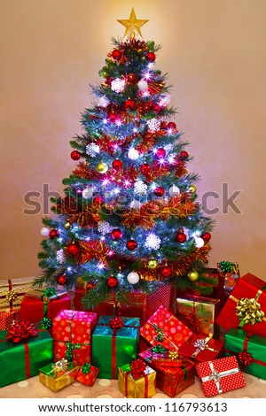 Photo of a decorated Christmas tree lit up with fairy lights and surrounded by gift wrapped presents, Santa has been!