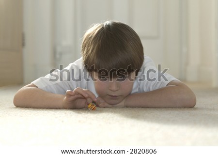 Boy playing marbles lying down on the carpet