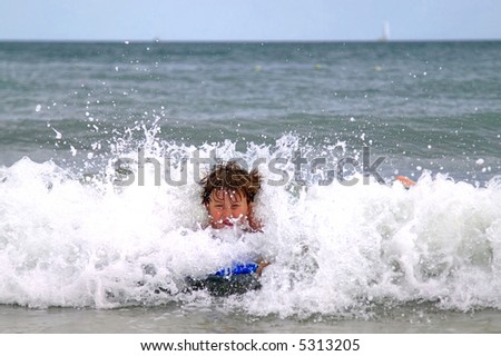 Boy on his boogie board with a wave crashing around him.
