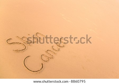Skin Cancer written in sand on a golden beach, a harsh reminder of how powerful and damaging the suns rays can be and an advisory message to use suntan cream.