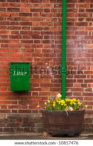 Green litter bin on a brick wall