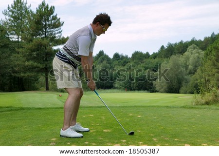 Golfer addressing the ball as he is about to tee off with an iron on a short par three