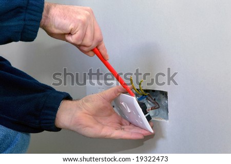 The hands of an electrician installing a power socket