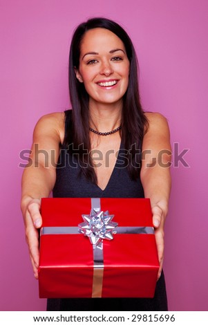 Attractive brunette woman giving you a present in red wrapping paper with silver ribbon and bow.