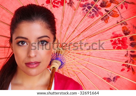Beauty shot of a young brunette woman with brown eyes holding a red chinese umbrella