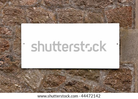 Blank white sign on an old stone wall, add your own message.
