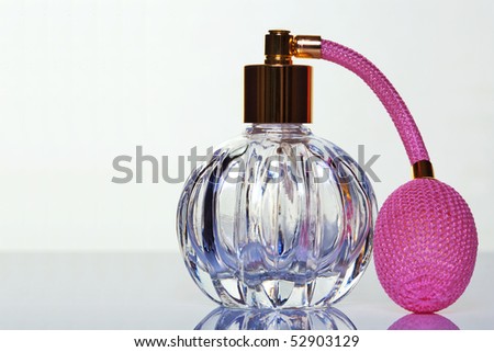 Crystal glass perfume atomiser with pink pump and gold lid, copy space on left of frame.