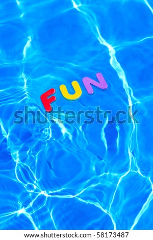 The word FUN made from foam letters floating on the water surface of a swimming pool