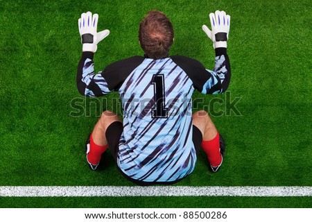 Overhead photo of a football goalkeeper standing on the goal line in ready position to face a penalty kick.