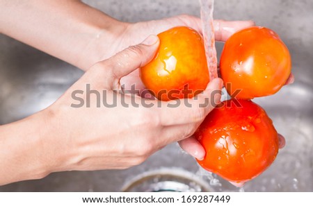 Female hands washing tomatoes at the kitchen sink