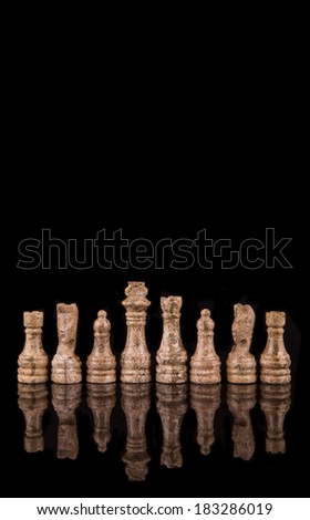 Brown pieces of stone made chess set over black background