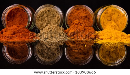 Mixed powdered spices in glass container over black background