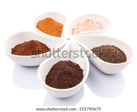 Cocoa powder, dried tea leaves and grounded coffee in a white ceramic container over white background