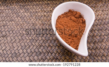 Cocoa powder for making drinks in a white ceramic container over wicker background