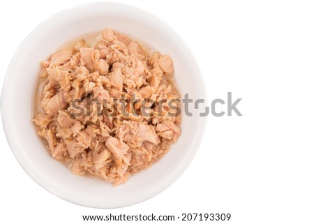 Flaked tuna pieces in a white bowl over white background