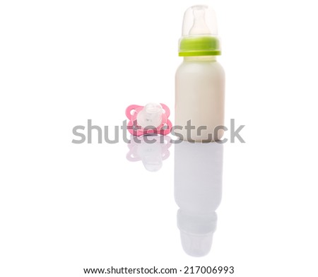 Baby pacifier and a bottle of baby formula milk over white background