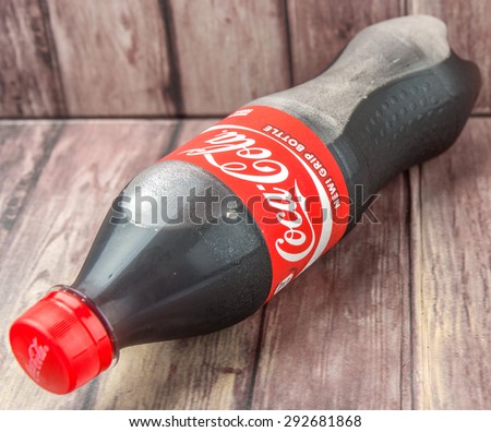 PUTRAJAYA, MALAYSIA - JULY 2ND, 2015. Coca Cola bottle on weathered wood. Coca Cola drinks are produced and manufactured by The Coca-Cola Company, an American multinational beverage corporation.