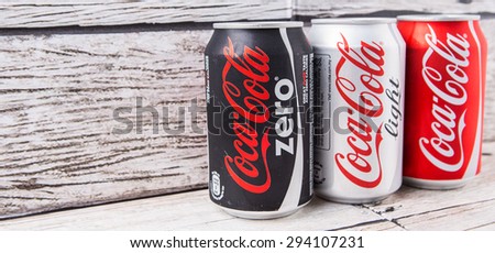 PUTRAJAYA, MALAYSIA - JULY 5TH, 2015. Coca Cola cans on aged wooden background. Coca Cola drinks are produced and manufactured by The Coca-Cola Company, an American multinational beverage corporation.