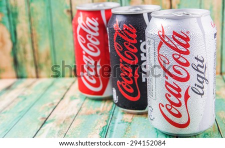 PUTRAJAYA, MALAYSIA - JULY 5TH, 2015. Coca Cola cans on aged wooden background. Coca Cola drinks are produced and manufactured by The Coca-Cola Company, an American multinational beverage corporation.