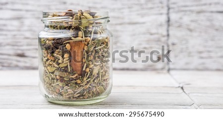 Mix herbs and spices in mason jar over weathered wooden background