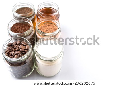 Coffee beans, coffee powder, creamer, cocoa powder, honey and processed tea leaves in a mason jar over white background