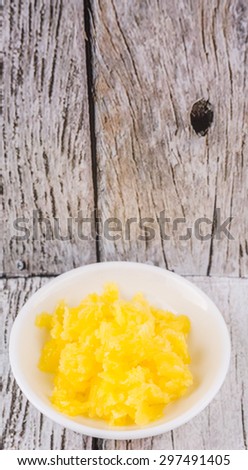 A bowl of Indian ghee in white bowl over wooden background