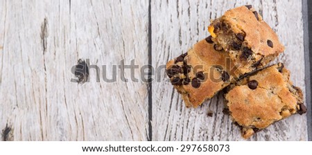 Sweet brownie dessert bar with chocolate chips over wooden background