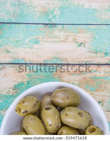 Pickled olive in a white bowl over wooden background