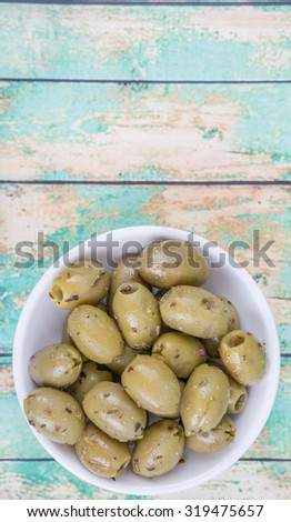 Pickled olive in a white bowl over wooden background