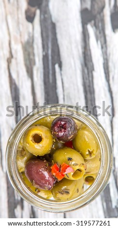 Pickled olive in a mason jar over wooden background
