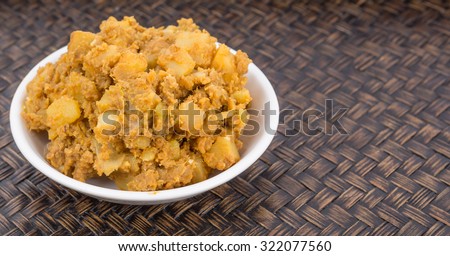 Minced beef and chopped potatoes filling for the popular Malaysian snack curry puff in a white bowl over wicker background