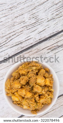 Minced beef and chopped potatoes filling for the popular Malaysian snack curry puff in a white bowl over wooden background