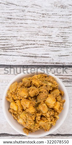 Minced beef and chopped potatoes filling for the popular Malaysian snack curry puff in a white bowl over wooden background