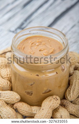 Peanut and peanut butter in a mason jar over wooden background