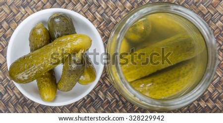 Dill pickles in white bowl over wicker background