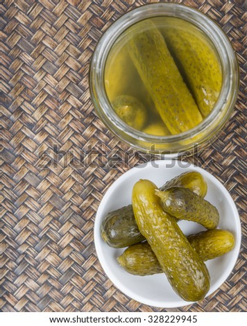 Dill pickles in white bowl over wicker background