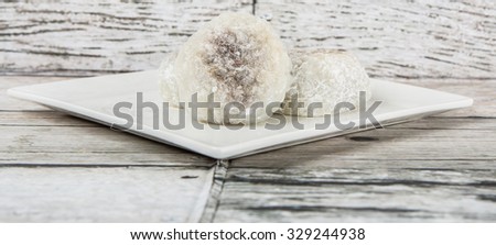 Japanese confection, round glutinous rice stuffed with sweetened red bean paste or locally known as daifukumochi in a white plate over wooden background