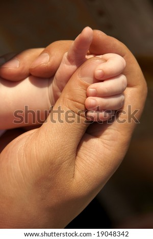 big hand holds little one's with thumb up