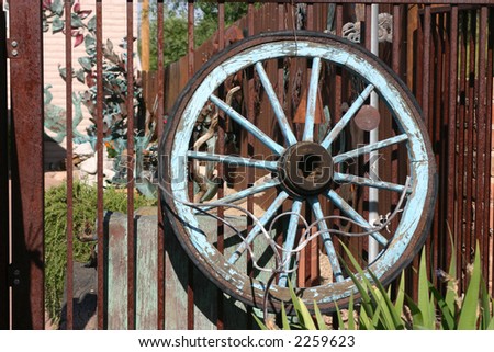 Old painted wagon wheel rests against a wrought iron fence in the art Colony of Tubac Arizona