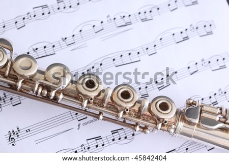 Silver flute superimposed on flute sheet music featuring a classical score
