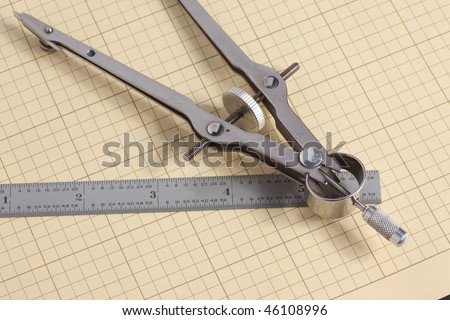 Macro view of mechanical drafting compass and fractional steel scale on yellow grid paper
