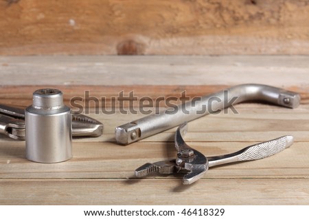 Locking pliers slip joint pliers socket wrench and wrench handle on a weathered wooden plank deck