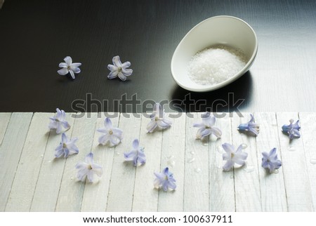 bath salts in porcelain dish and flowers on wooden table