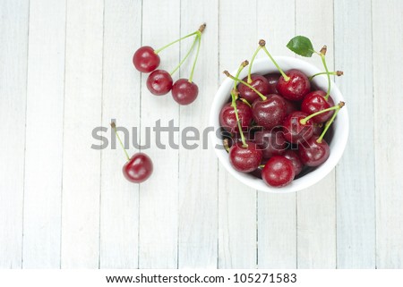 sour cherries in china dish on white wooden table, directly above