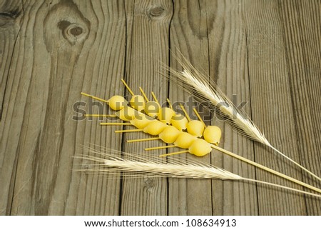 dry pasta as wheat ear and real wheat ears, wooden table